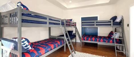 Une chambre avec des lits superposés, un ventilateur de plafond et un tapis à motifs géométriques.