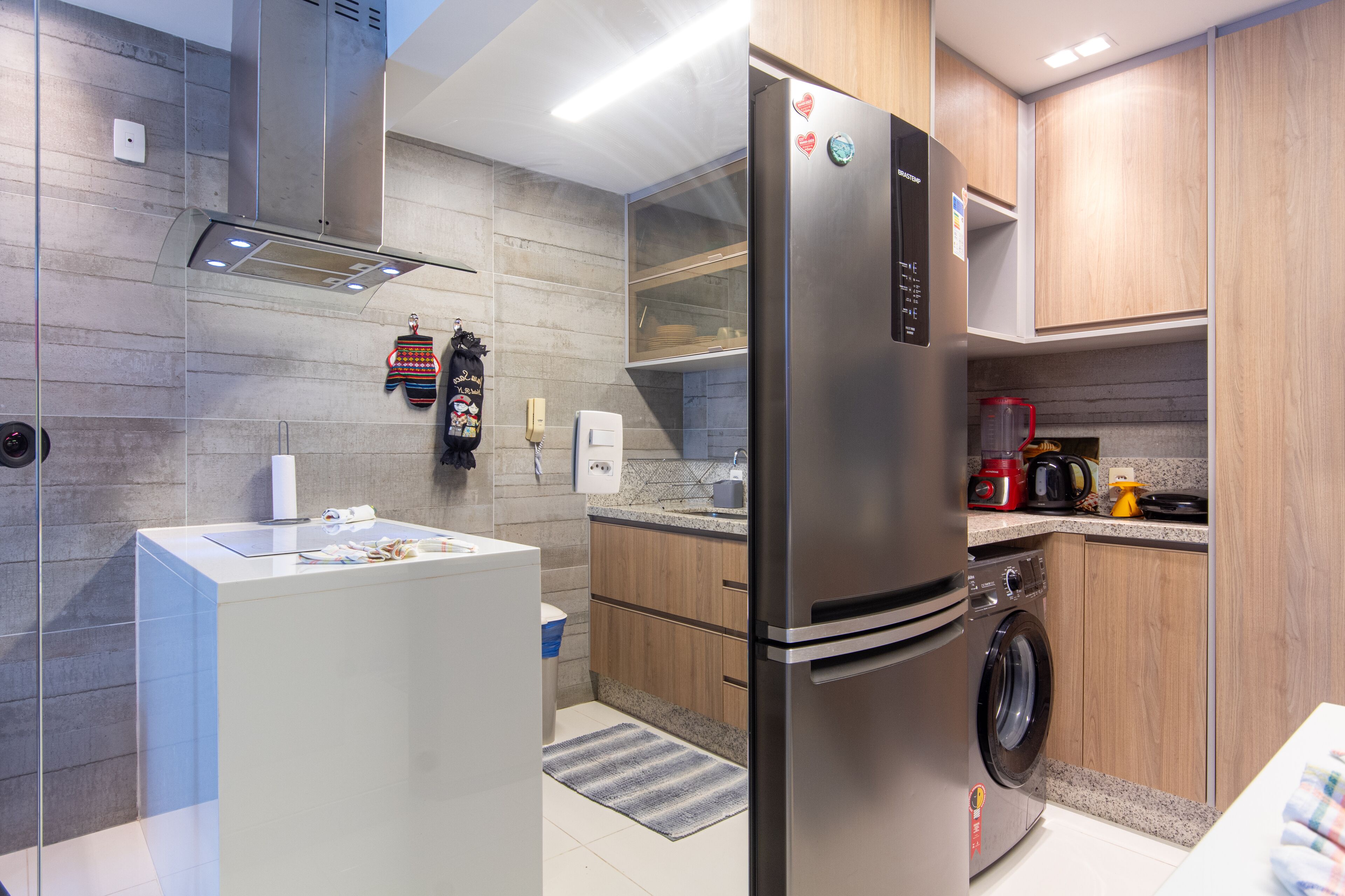 A modern kitchen with stainless steel appliances, wooden cabinets, and a built-in washing machine.