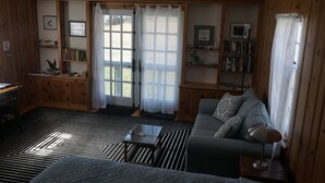 Een gezellige kamer met een bank, een salontafel, een boekenkast en een raam met gordijnen.
