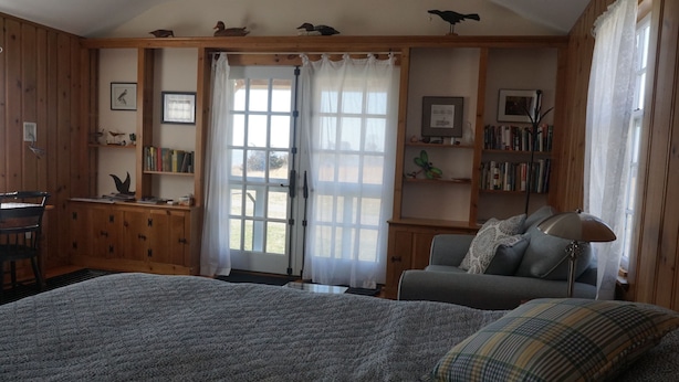 Een gezellige kamer met een groot bed, een bureau en een boekenplank.