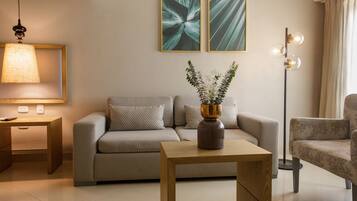 Ein modernes Wohnzimmer mit einer Couch, einem Couchtisch, einer Stehlampe und zwei gerahmten Kunstwerken an der Wand.