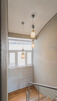 Una escalera con barandilla de cristal, suelo de madera y lámparas colgantes.