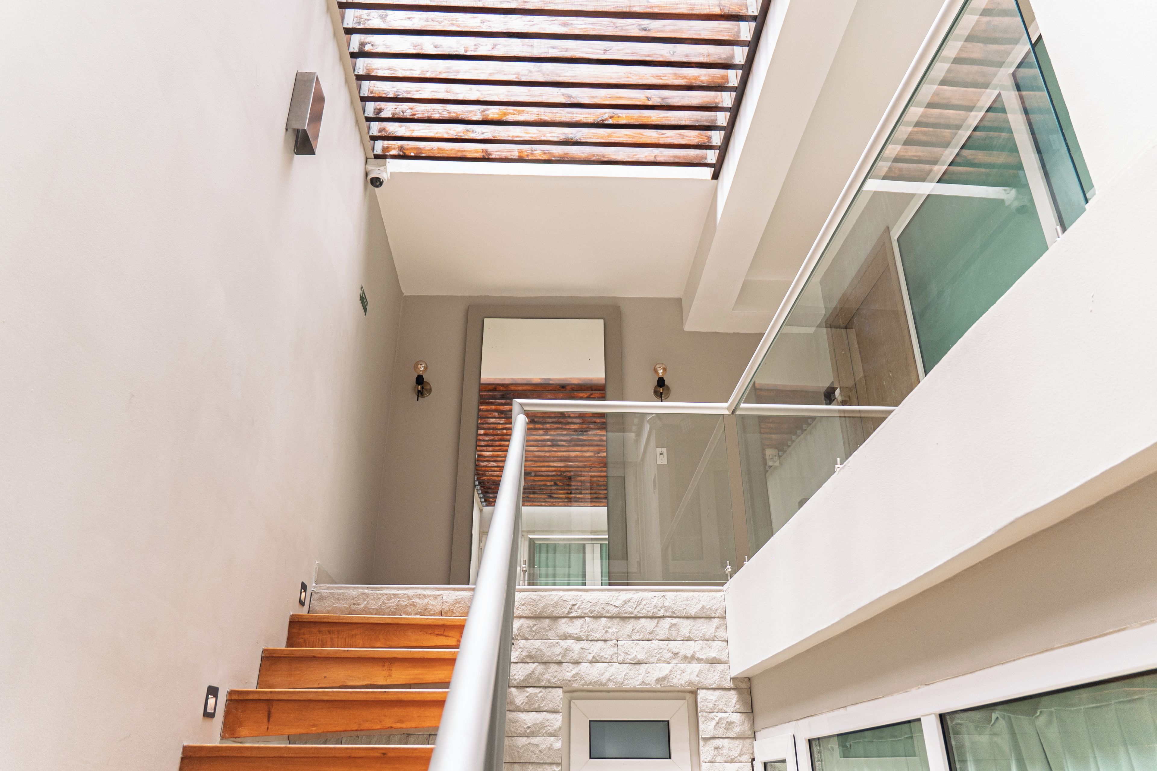 Una escalera de madera con peldaños que conducen a un rellano con barandilla de cristal.