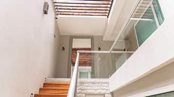 Una escalera de madera con peldaños que conducen a un rellano con barandilla de cristal.