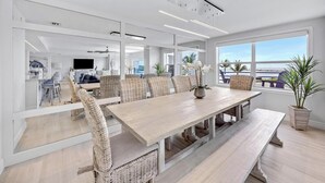 A modern dining area with a long table, wicker chairs, and a view of the ocean. - Sublime Sunsets at the Truman Annex in Key West (Key West)