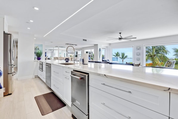 A modern kitchen with white cabinetry, a dishwasher, and a large island.