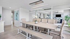 A modern dining area with a long table, wicker chairs, and a bench. - Sublime Sunsets at the Truman Annex in Key West (Key West)