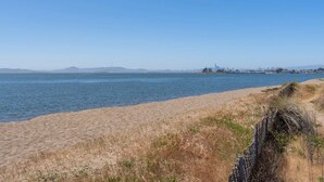A beach with a clear view of the water and distant city skyline. - Coastal Zen Den (Alameda)
