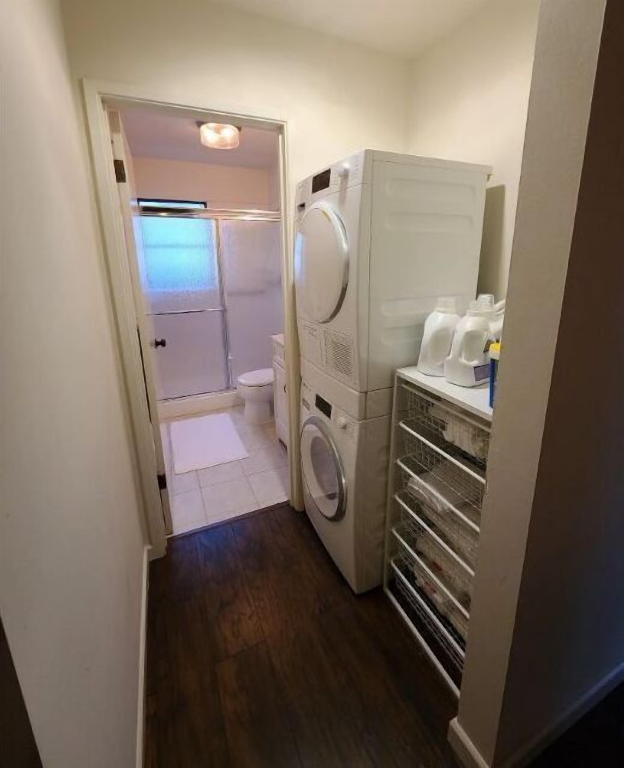 A laundry room with a washing machine, dryer, and shelves with detergent bottles.