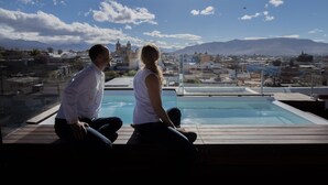 A couple sitting by a pool with a cityscape and mountains in the background. - SUITE DAWN (Oaxaca de Juárez)