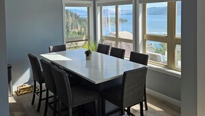 A dining area with a large table, chairs, and a view of a body of water and mountains. - FULLY RENOVATED LAKEVIEW COTTAGE / PET FRIENDLY - LA CASA (Kelowna)