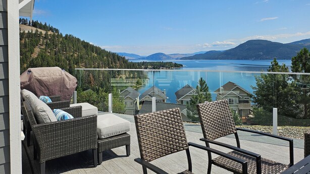 A balcony with wicker furniture overlooking a lake and mountains. - FULLY RENOVATED LAKEVIEW COTTAGE / PET FRIENDLY - LA CASA (Kelowna)
