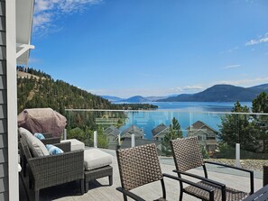 A balcony with wicker furniture overlooking a lake and mountains. - FULLY RENOVATED LAKEVIEW COTTAGE / PET FRIENDLY - LA CASA (Kelowna)