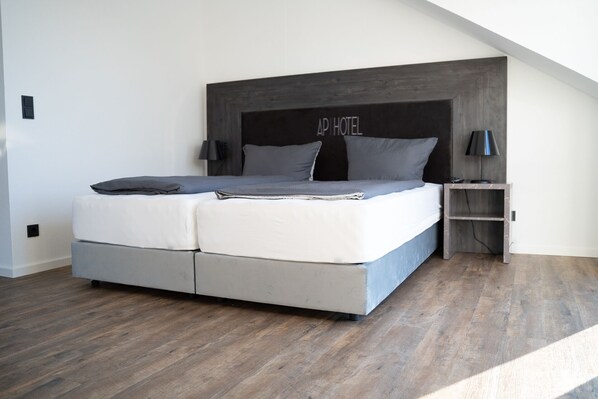 A modern bedroom with a large bed, a nightstand, and a headboard that reads "AP HOTEL". - AP Hotel Mannheim Viernheim (Viernheim)
