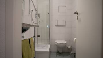 A small, clean bathroom with a shower, toilet, and sink.
