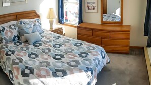 Ein Schlafzimmer mit Bett, Schminktisch, Spiegel und Bildern an den Wänden.