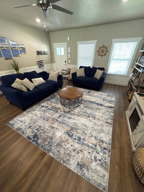 A living room with a sectional sofa, a coffee table, and a patterned rug.