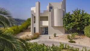 A modern two-story building with a flat roof, large windows, and a paved driveway. - Anssami Villa  (Rhodes)