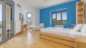 A modern bedroom with a large bed, a desk, and a view of the outdoors. - Anssami Villa  (Rhodes)