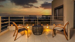 A balcony with two wicker chairs, a round table, and candles. - Anssami Villa  (Rhodes)