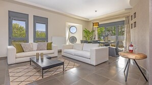 A modern living room with two white sofas, a coffee table, and a dining area with a round table. - Anssami Villa  (Rhodes)