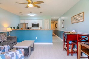 A modern kitchen with white cabinets, a microwave, and a ceiling fan.