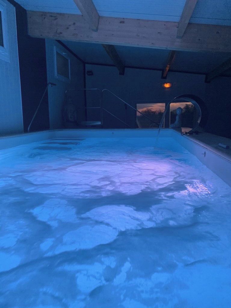 Una piscina interna con vista sul cielo attraverso una finestra.