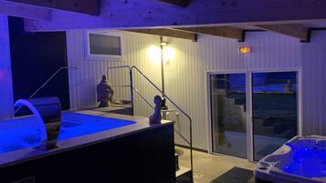 Un espace bien-être comprenant un jacuzzi, une statue et un escalier menant à une porte-fenêtre coulissante.