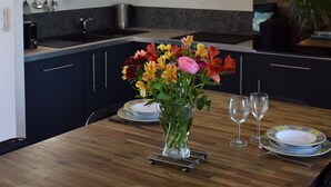 Une cuisine moderne avec des meubles de couleur sombre, un îlot central en bois et des luminaires suspendus.