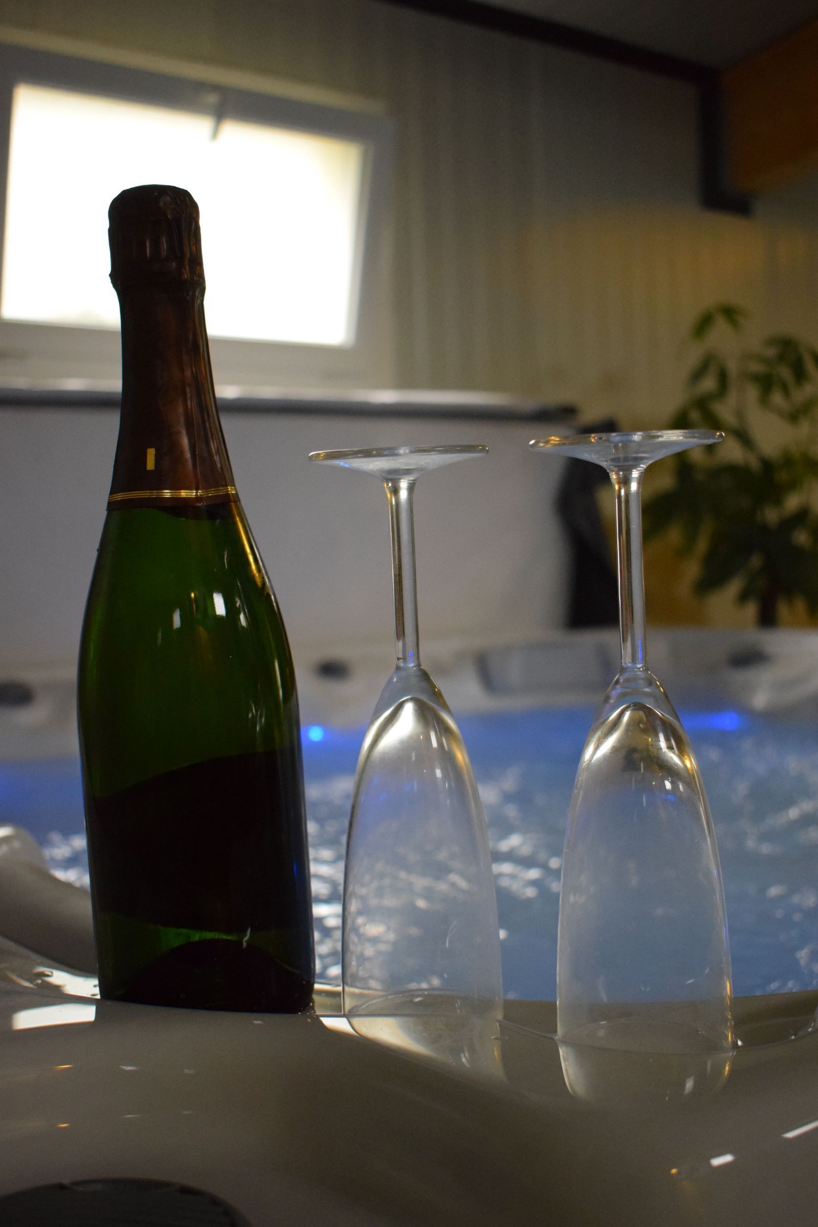 Une bouteille et deux verres sont posés sur une table, avec une fenêtre en arrière-plan.