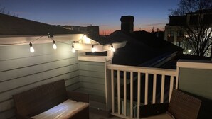 A rooftop patio with wicker furniture, string lights, and a candle on a table. - ⭐️Walk to Forsyth Park & River St•Historic Downtown•Private Patio⭐️ (Savannah)