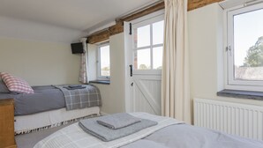 Una camera da letto con un letto, una finestra, un termosifone e una televisione appesa al muro.