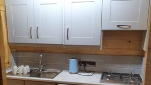 A compact kitchen with white cabinets, a stainless steel sink, a dishwasher, and a gas stove.