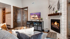 Una sala de estar con chimenea, televisión y pared de piedra.
