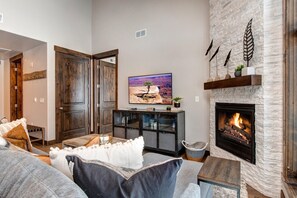Una sala de estar con chimenea, televisión y pared de piedra.