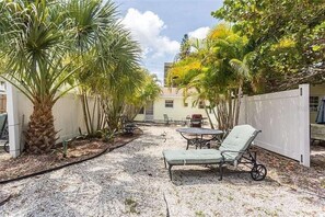 Relax in a serene outdoor space surrounded by lush tropical plants and a palm tree, with comfortable seating options.