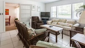 Una sala de estar con un sofá, sillones, una mesa de centro y una televisión.