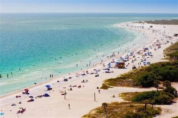 Enjoy the serene beach scene with a wide expanse of sandy shore and clear waters.