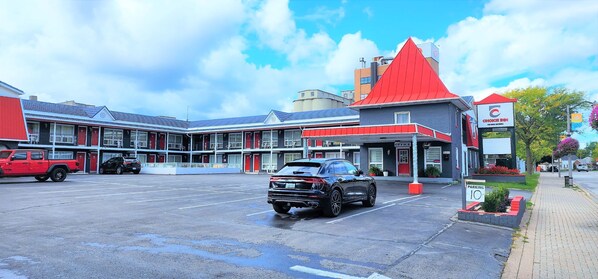 Ein Motel mit rotem Dach, einem Parkplatz und einem Schild mit der Aufschrift 'Choice Inn'.