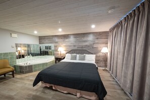 Ein Schlafzimmer mit einem großen Bett, einer Sitzecke, einer Badewanne und einem Spiegel.