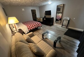 Ein Hotelzimmer mit Bett, Sofa, Fernseher und Schreibtisch.