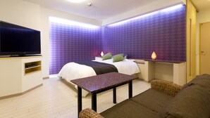 A modern hotel room with a bed, a flat-screen TV, a small table, and a sofa. - Hotel Xenia Juso - Adults Only (Osaka)