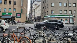 A city street with buildings, a bicycle parking area, and a FamilyMart store. - Hotel Xenia Juso - Adults Only (Osaka)