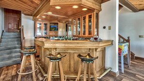 A kitchen with wooden cabinetry, a bar area with stools, and a television.