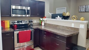 A modern kitchen with dark cabinets, stainless steel appliances, and a granite countertop. - ❤️Executive Suite❤️By 2 Shopping Centres, Costco ... (Grande Prairie)