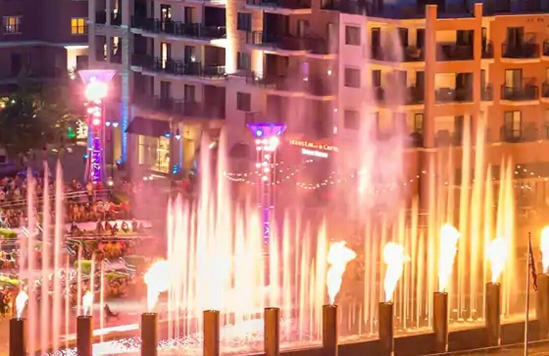 A building with multiple balconies and a fountain display in front.