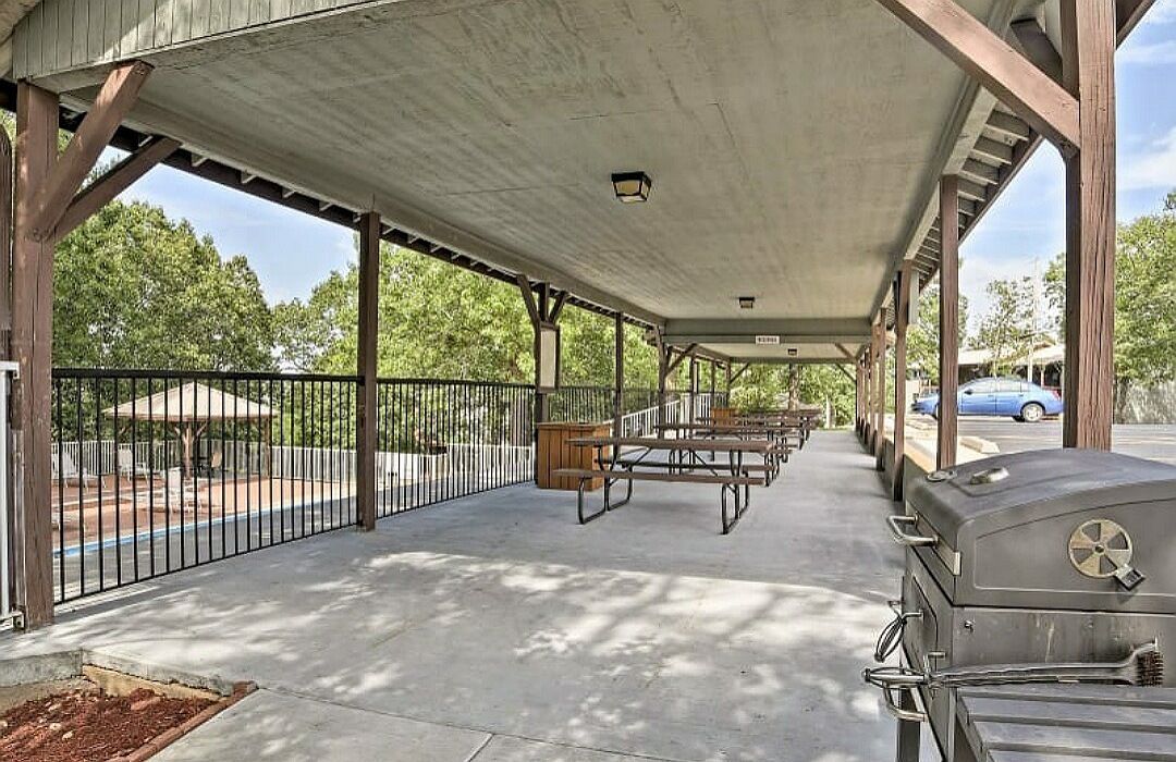 An outdoor covered patio area with picnic tables and a barbecue grill.