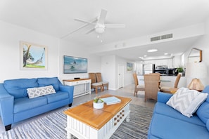 A modern living room with a blue sofa, a wooden coffee table, and a ceiling fan.