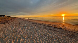 Ranta, jossa näkyy auringonlasku, laituri ja taustalla rakennuksia.