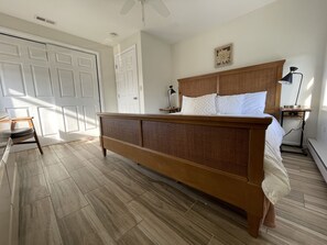 Une chambre à coucher avec un lit en bois, une table de chevet, une chaise et une porte.